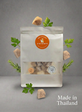 灰色背景上的白色寵物食品包裝袋，配有紅色標籤，周圍擺放著寵物零食及肉片。